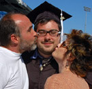 Mom and Dad kissing their son on the cheek after his college graduation