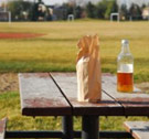 Pack it up, pack it in, let me begin. Malt liquor bottle alone on picnic table with paper bag