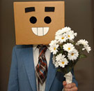 Guy with a smiling box over his head and a bouquet of flowers at a girl's door