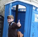 Portopotty with a guy giving thumbs up