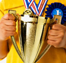 Kid holding a gold trophy and wearing medals