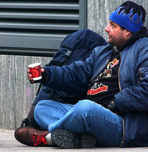 Homeless man begging for change with a cup