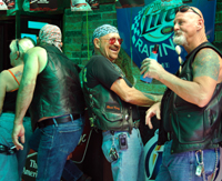 Four biker guys in leather standing at a bar