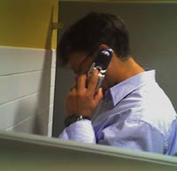 Guy on cell phone while using urinal.