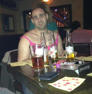 Guy drinking beers at a bar in a dress