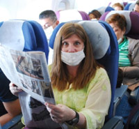 Woman on airplane wearing flu mask