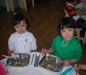 Korean kids eating lunch at school on metal trays