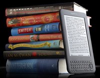 Stack of books next to an Amazon Kindle