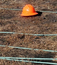 Orange construction hard hat laying on the ground next to downed power cables