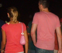 Guy in a pink shirt that matches his girlfriend's purse