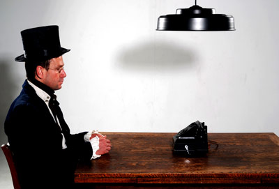 Man in a top hat waiting by the phone on a table