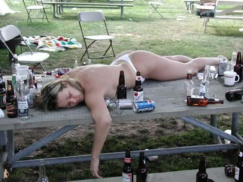 Woman passed out drunk on a picnic table amidst empty beer bottles