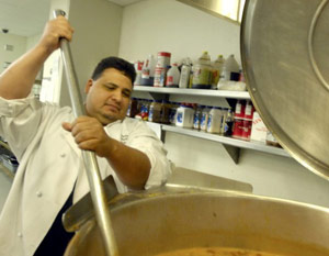 Soup kitchen volunteer stirring soup ladle