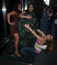 Three girls humping a statue of a lion