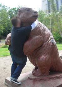 Guy hugging a bear statue in public