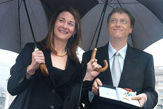 Bill and Melinda Gates standing under umbrellas