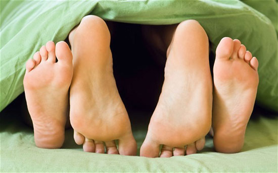 A couple's feet at the foot of the bed