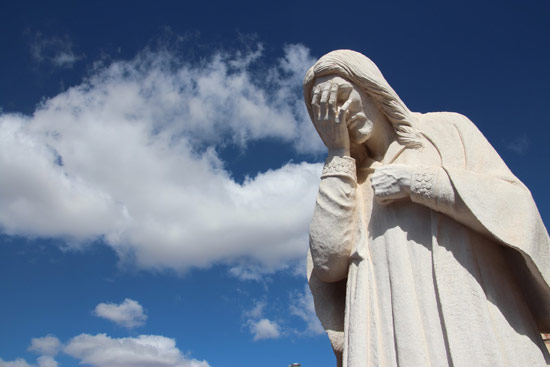 Statue of Jesus weeping with sky in background