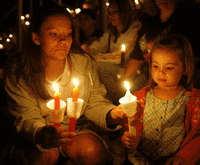 Mom and daughter holding paper candles in a vigil