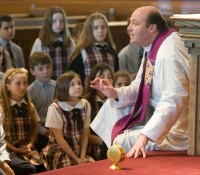 Catholic priest teaching young kids in a church