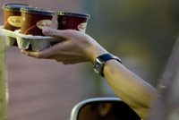 Reaching to hand cups of coffee at drive-thru window