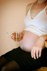 Pregnant girl holding a drink and cigarette