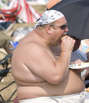Fat guy eating on the beach
