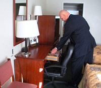 Man picking up a Bible out of a hotel room drawer