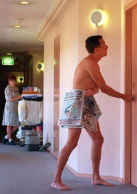 Guy in just newspaper outside his hotel room door