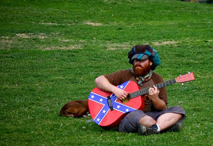 Liberal hippie college student guy playing acoustic guitar on the quad
