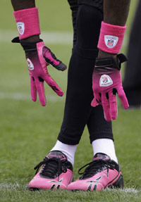 NFL player reaching down to his toes with pink gloves and pink cleats