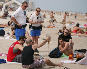 Police make a guy pour liquor out on the beach