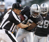 Referee trying to take the football from an Oakland Raiders player on the field