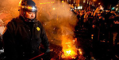 San Francisco cop next to a bonfire in a street riot