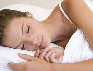 Woman in white sleeping on a bed