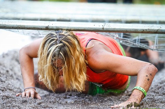 Woman goes under a barbed wire obstacle course