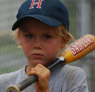 Sad boy holding a Little League baseball bat
