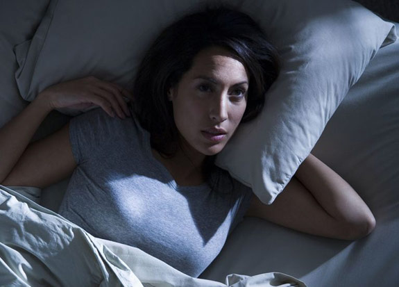 Woman lying in bed can't fall asleep with her eyes open