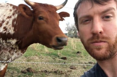 Court Sullivan standing next to a cow