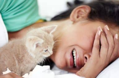 Woman crying herself to sleep in bed with a kitten