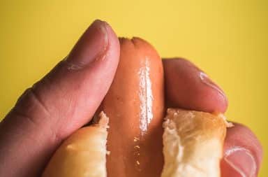 Person holding a hot dog peeking out of a bun