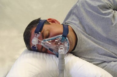 Man wearing sleep apnea mask in bed