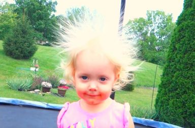 Toddler on a trampoline has crazy blonde hair standing up