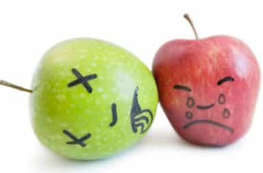 Apples with faces drawn on them in black marker