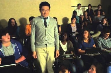 Man standing up in college classroom being stared at