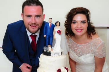 Couple next to a wedding cake with themselves on it