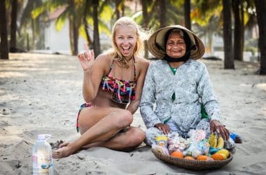 Woman backpacking Asia sitting on the beach with older woman