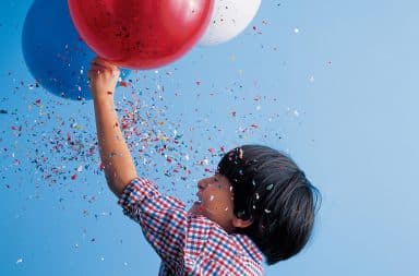 Boy holding a balloon with confetti raining down