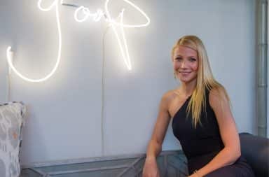 Gwyneth Paltrow posing by her Goop neon sign
