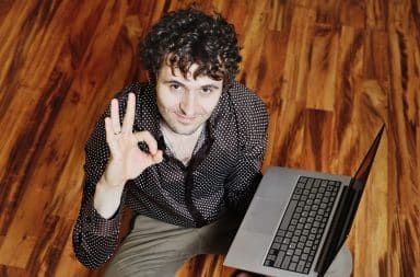 Man holding a laptop and the OK sign with his hand